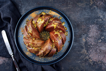 Exotically bundt marble passion fruit rum cake with icing sugar glaze, fresh fruit pulp topping and muscovado brown sugar served as top view on a plate with copy space