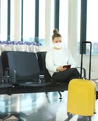 Waiting at the airport.,using smartphone, woman wearing  surgical face mask .