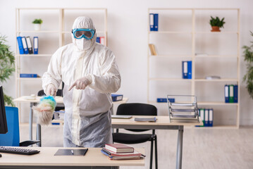 Old male contractor cleaning the office holding feather