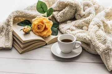 Morning coffee. A cup of coffee on a wooden table and an open book against a background of a bouquet of spring flowers. Still life concept. Cozy morning.