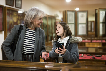 Cute curious tween girl browsing internet on smartphone in search of information about showpieces...