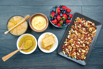 fresh assorted honey, nuts, strawberries and blueberries on a wooden background. healthy organic vitamin food.
