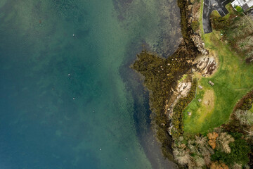 Aerial top down view on a small picnic area by the ocean. Wooden tables and seat. Blue color water. Roundstone, county Galway, Ireland