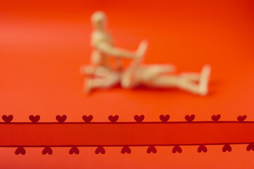 Red ribbon with hearts in focus. Couple making love out of focus. Juicy red background. Adult...