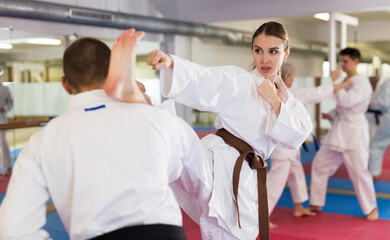 Caucasian man and woman in kimono sparring during group karate training. © JackF