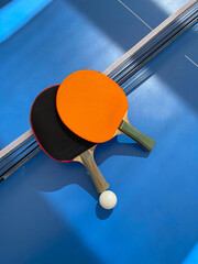 Tennis rackets and ball lie on a blue tennis table, top view. Ping pong rackets with a ball