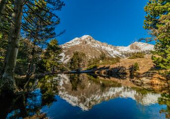 Fototapeta na wymiar Snowy mountain reflected on the water of a lake in the Pyrenees, Spain. Mountain landscape.