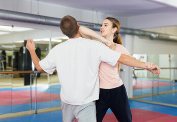Fototapeta na wymiar Active girl conducts painful grip on self-defense training in the gym