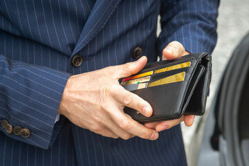 Close up of a businessman in a suit opens his business leather wallet