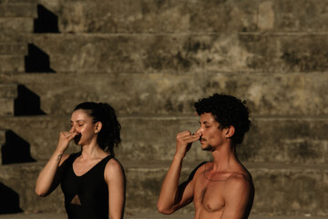 Couple doing yoga fitness exercises sport in the streets with open arms, stairs background....