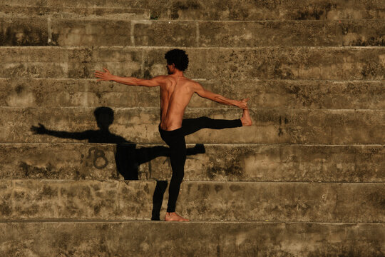 Man doing yoga fitness sport in the streets with stairs background © Thiago Gomes