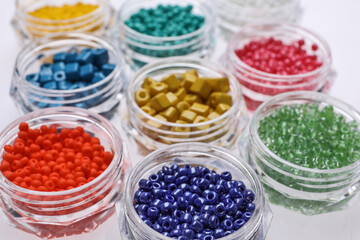 Plastic containers with different beads on white background, closeup