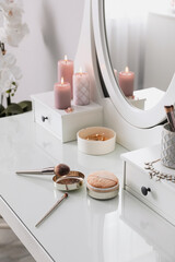 Wooden dressing table with decorative elements and makeup products in room