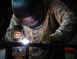 The two handymen performing welding and grinding at their workplace in the workshop, while the...
