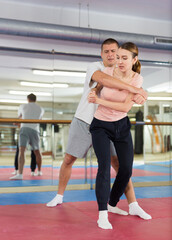 Fototapeta na wymiar European woman learning elbow strike move during self-defense training.