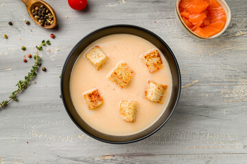 salmon cream soup on black bowl on grey wooden table top view