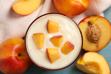 Naklejka na ściany i meble Tasty peach yogurt with pieces of fruit in glass on light blue wooden table, flat lay