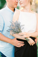 Man hugs a woman with a lavender bouquet. Portrait