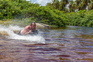Homem deslizando numa prancha sob agua num rio