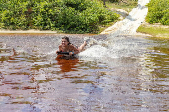 Mulher deslizando numa prancha sob agua num rio