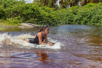 Mulher deslizando numa prancha sob agua num rio