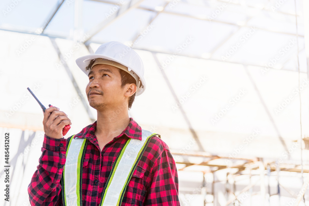 Poster asian engineer foreman architect worker man working at building construction site talking with radio