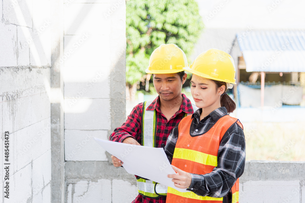 Poster architect and client discussing the plan with blueprint of the building at construction site. asian 