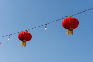 A low angle shot of Chinese sky lanterns hanging on a wire with the clear blue sky on the background