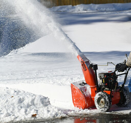 removing snow on the driveway of the house by snow blower