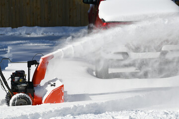 removing snow on the driveway of the house by snow blower