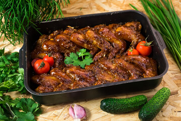 Chicken wings baked in barbecue sauce in a metal tray. Home Cooking. Rustic style.