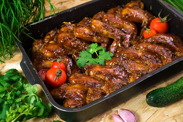 Chicken wings baked in barbecue sauce in a metal tray. Home Cooking. Rustic style.
