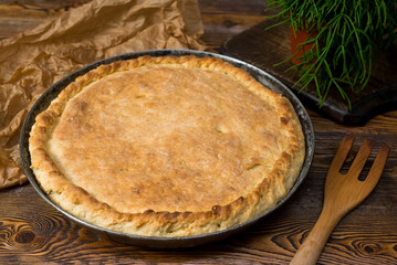 Closed cabbage pie made with yeast dough on a metal baking sheet. Traditional Russian cuisine.