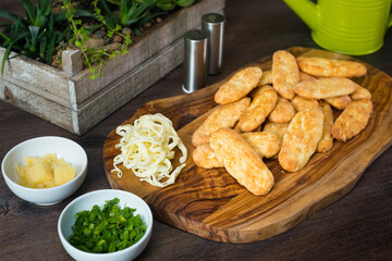 Cheesy breadsticks. Wooden board with cheese bread fingers. Food to eat with your hands. Homemade baking.