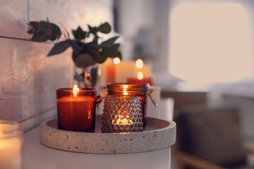 Burning candles on mantel near white wall indoors, space for text