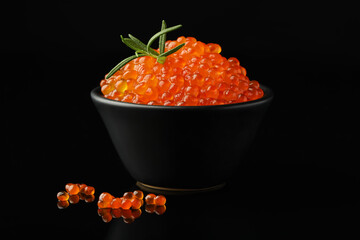 Delicious red caviar and rosemary on black background