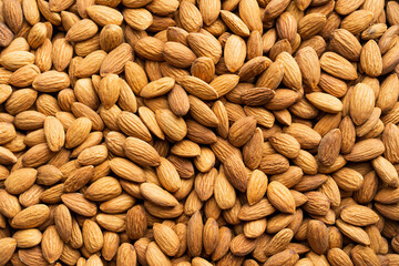 Background of organic almonds. Natural pure almond nuts. Scattered almond grains. Roasted almond for snack. Healthy eating with food from nature