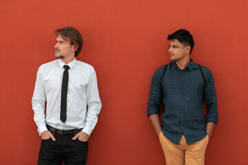 Casual multiethnic startup business men during break from work in front of red wall outside