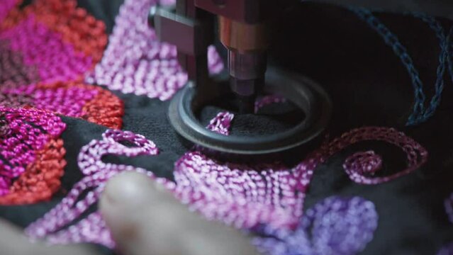 Extreme close up of sewing machine stitching flower pattern. Making a dress.