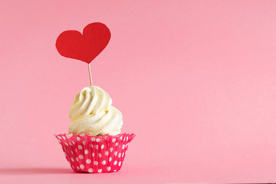 Sweet vanilla cupcake decorated red heart on pink backgroud. Concept Valentine's Day
