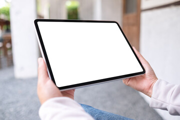 Mockup image of a woman holding digital tablet with blank white desktop screen in the outdoors