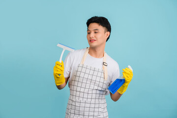 Photo of Asian young cleaning a mirror with a spray and squeegee, isolated on light blue background