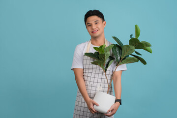Asian young handsome gardener in white apron. Studio shot on light blue background