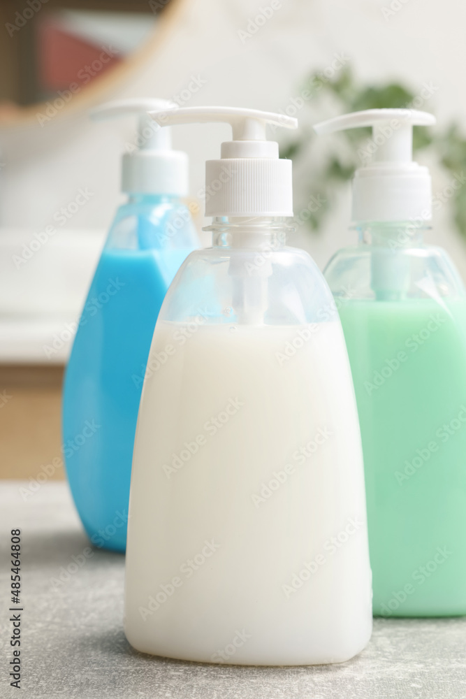 Sticker Dispensers of liquid soap on light grey table in bathroom