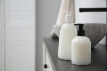 Fototapeta na wymiar Dispensers of liquid soap on countertop in bathroom. Space for text