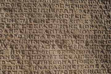 Ancient greek inscriptions on the wall of archeological ruins close-up