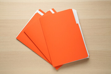 Orange files with documents on wooden table, top view