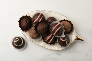 Different delicious chocolate truffles on white marble table, flat lay