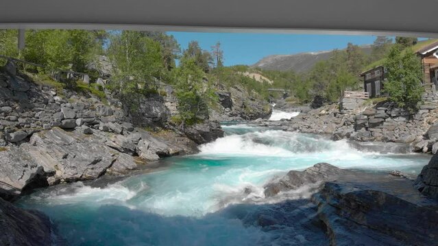 A drone is flying under the bridge and above the powerful stream of water