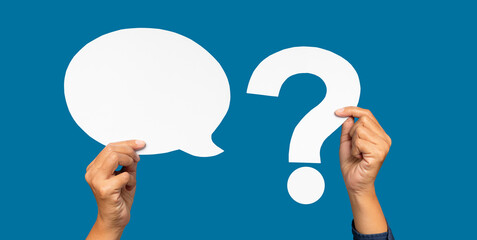 A speech bubble and question mark symbol concept. Hand holding a blank white speech bubble and a white question mark against a blue background.